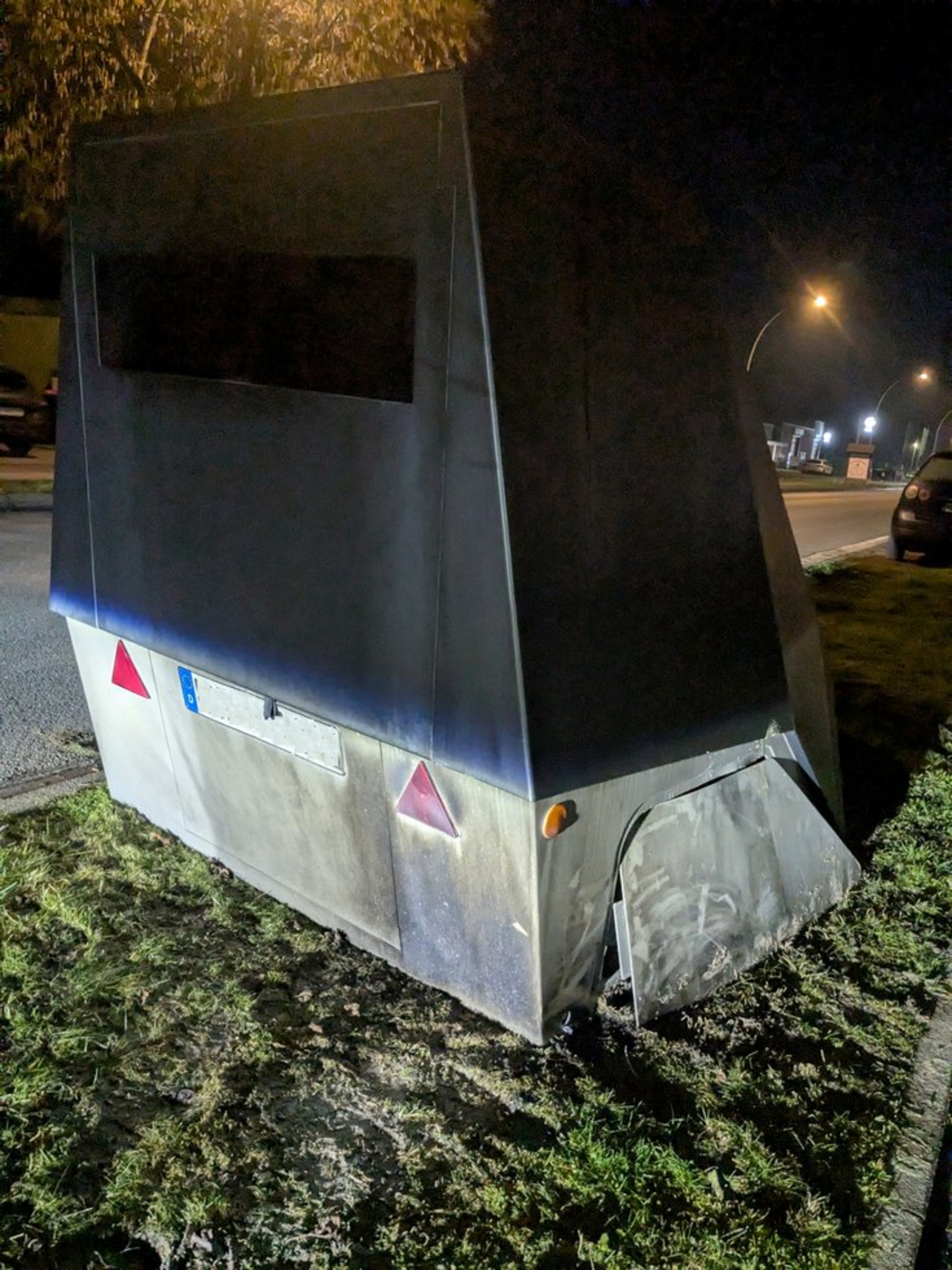 Ein Geschwindigkeitsmessgerät steht am Straßenrand. Das Gehäuse ist an der rechten Seite geöffnet.