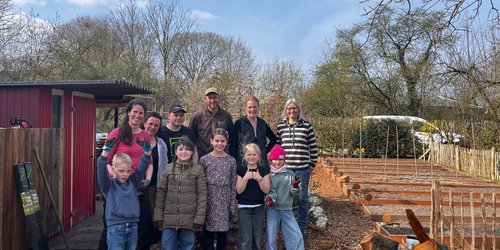 Schülerinnen, Schüler und Erwachsene vor dem neuen Gemüsegarten der Montessori Schule