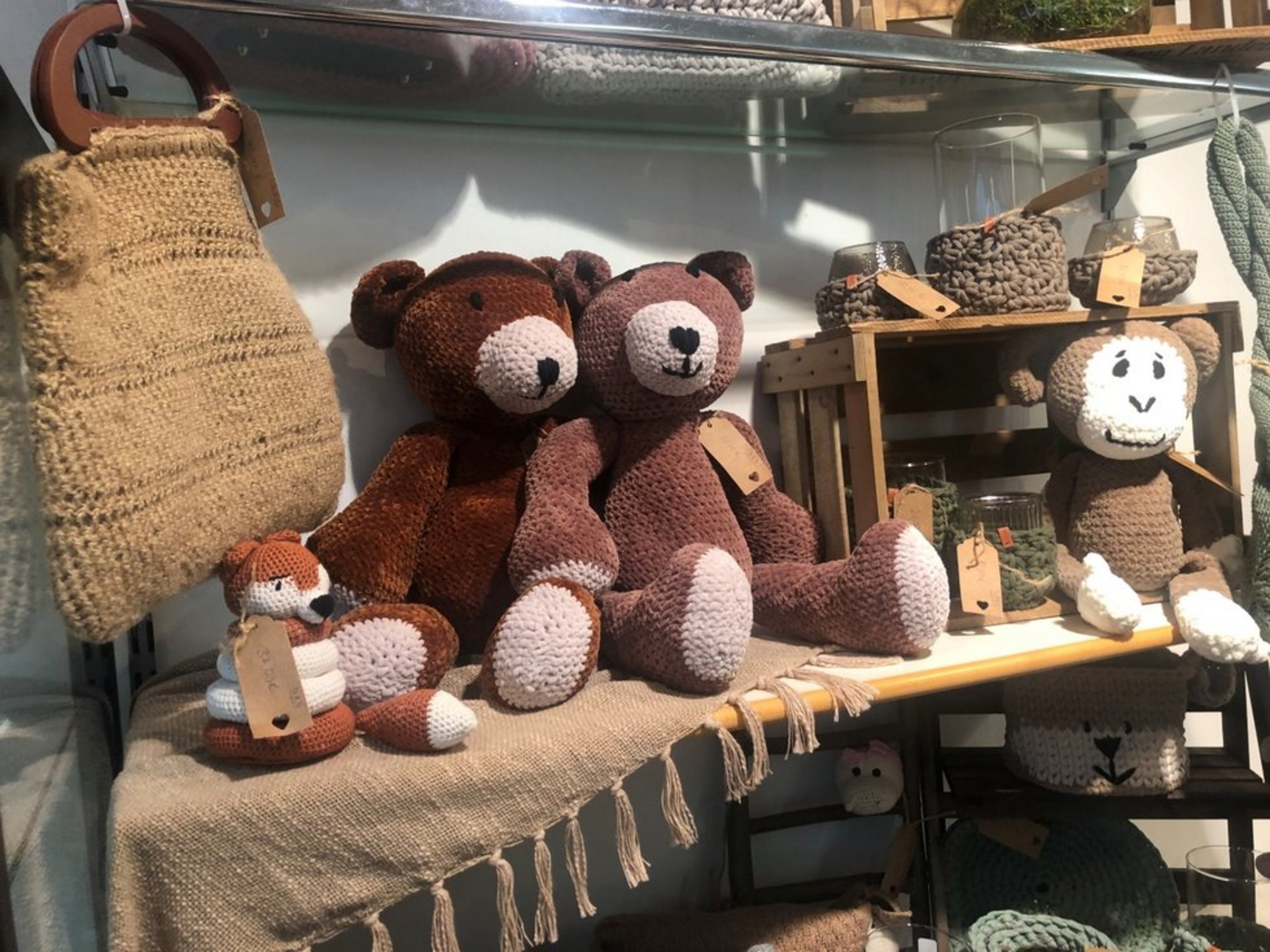 Gehäkelte Stofftiere und handgefertigte Dekorationsartikel aus Wolle und Garn auf einem Verkaufsregal eines Kunsthandwerksstands.