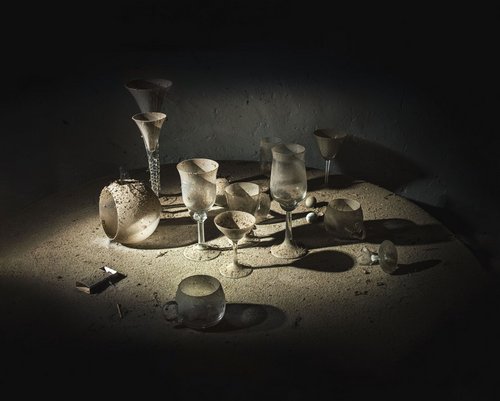 Auf einem Tisch steht und liegt Geschirr, das mit Staub bedeckt ist.