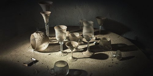 Auf einem Tisch steht und liegt Geschirr, das mit Staub bedeckt ist.