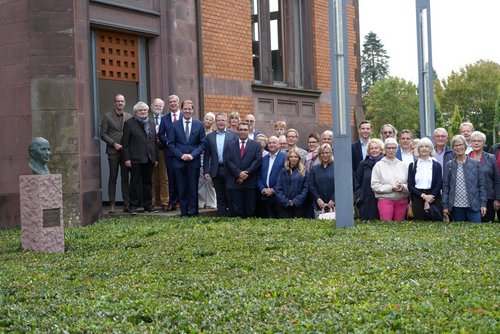 Landrat, Bürgermeister, Künstler, Autor und Gäste der Feierstunde stehen vor dem Gebäude neben einer neu enthüllten Büste mit Gedenktafel.