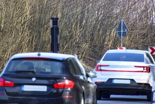 Zwei Autos fahren auf ein Tempomessgerät zu.