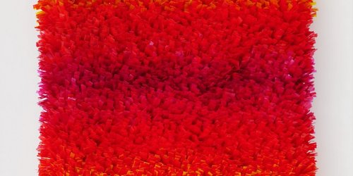 Ein Kunstwerk bestehend aus Fransen in den Farben gelb, orange und rot.