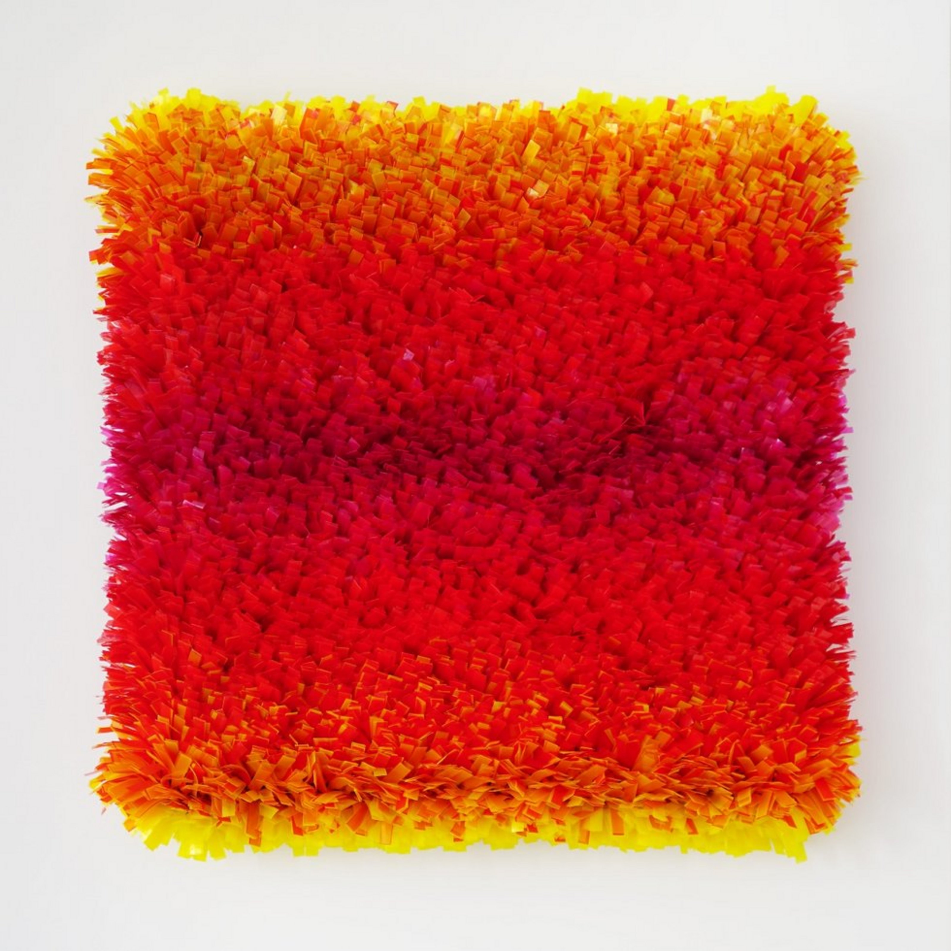 Ein Kunstwerk bestehend aus Fransen in den Farben gelb, orange und rot.