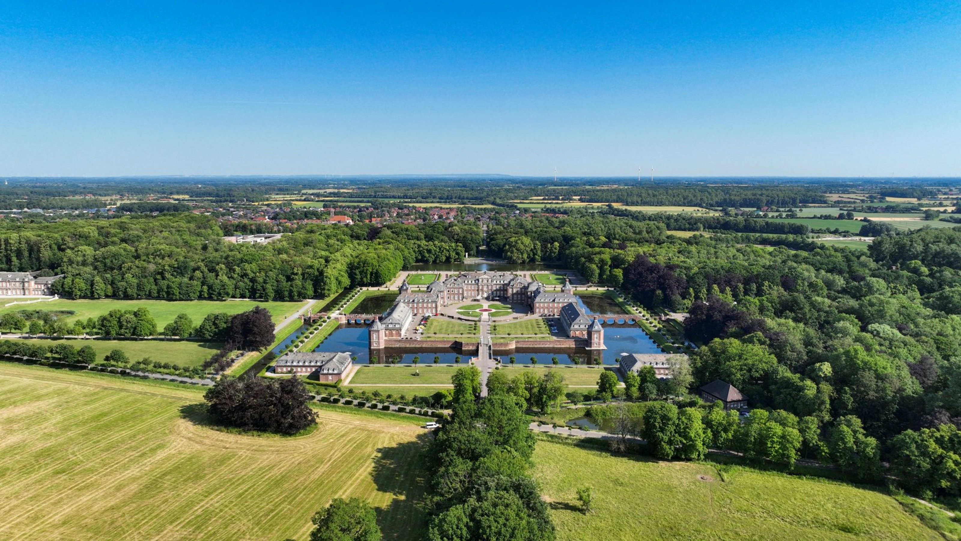 Luftaufnahme von Schloss Nordkirchen, umgeben von Wassergräben, Parkanlagen und Wäldern.