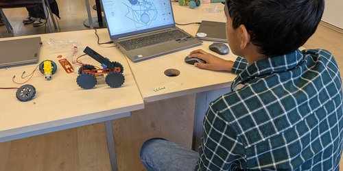 Ein Junge sitzt vor einem Laptop.