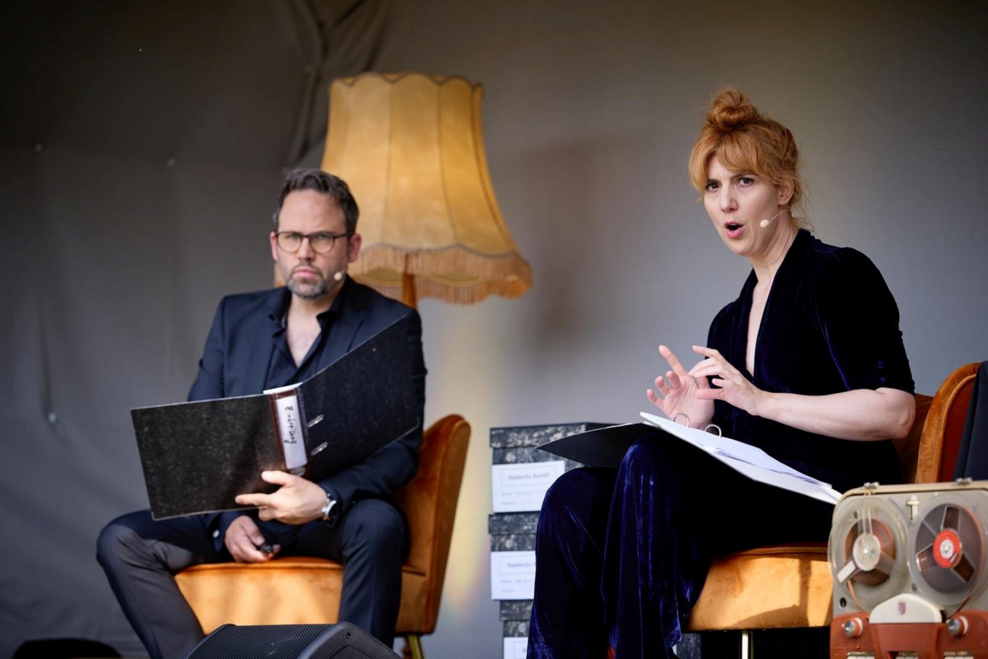 Ein Mann und eine Frau sitzen auf zwei Sesseln. Sie haben ein HEadset auf.