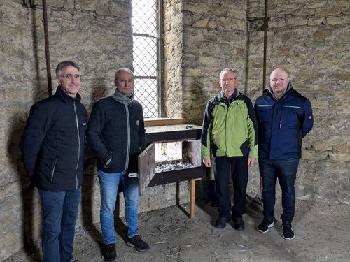 Vier Männer stehen neben einem Nistkasten für Wanderfalken im Turm des Billerbecker Doms