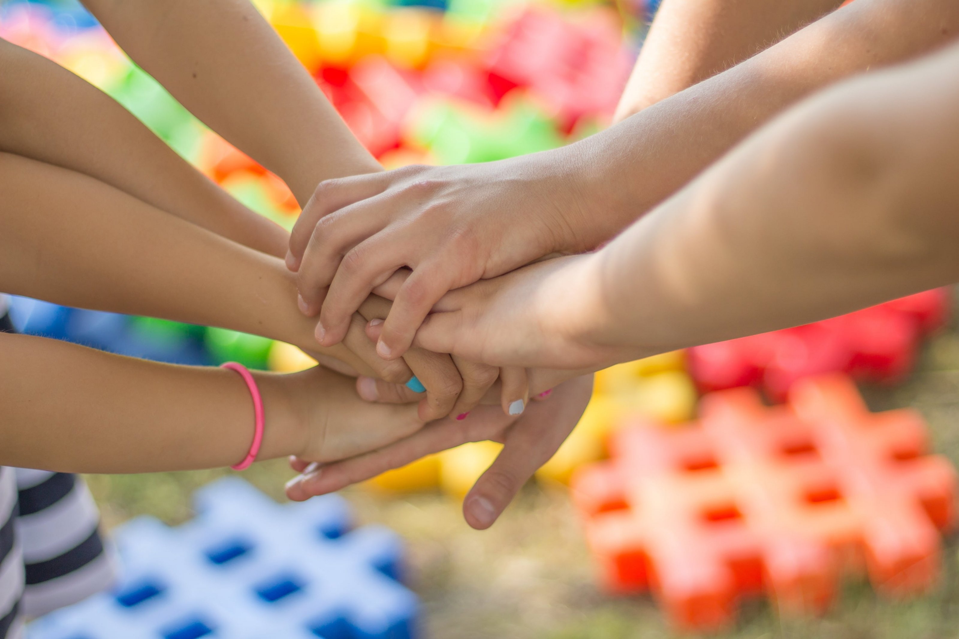 Mehrere Kinder stricken ihre Hände in einem Kreis zusammen.