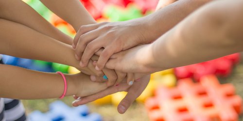 Mehrere Kinder stricken ihre Hände in einem Kreis zusammen.