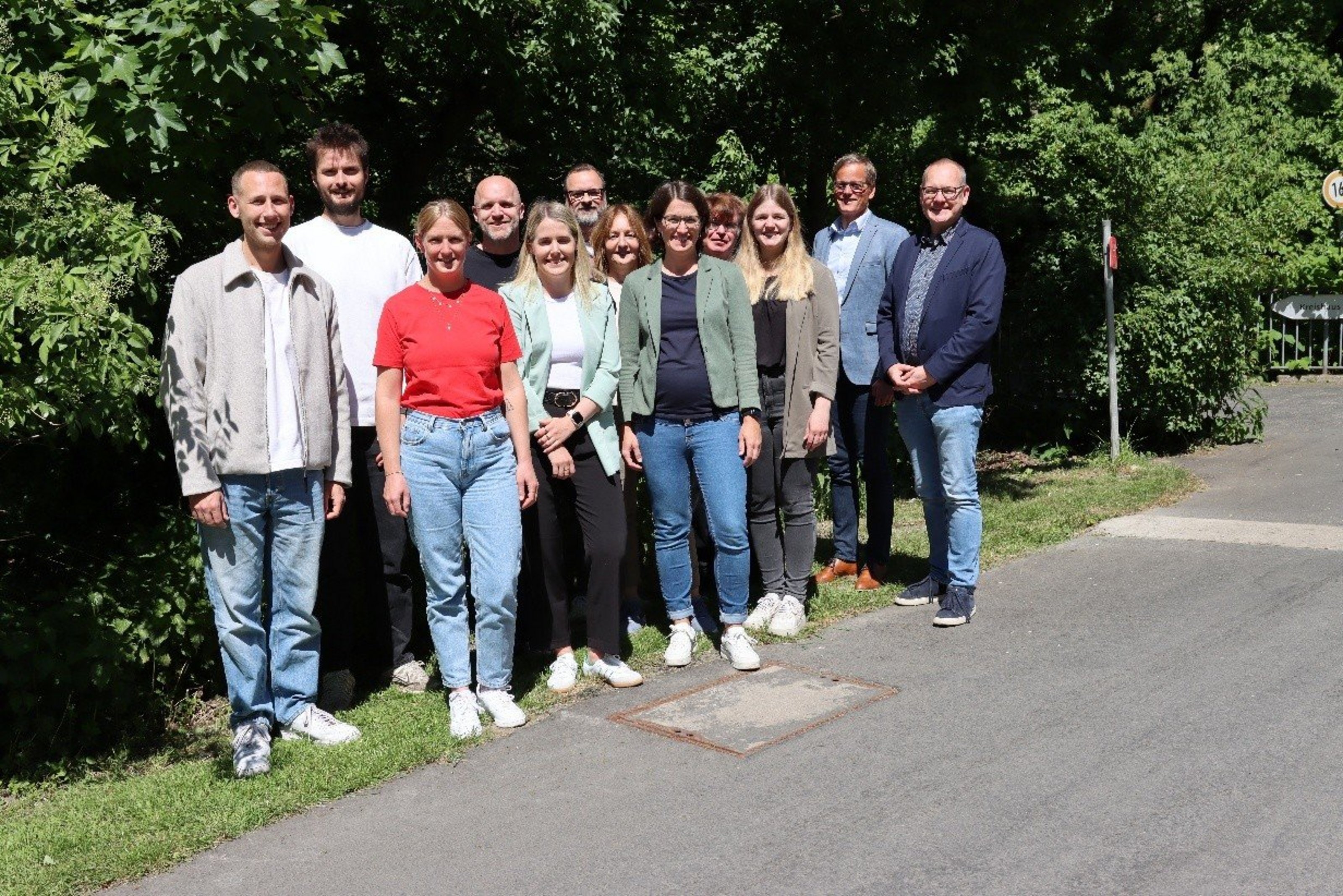 Gruppenfoto von zwölf Projektbeteiligten des Projekts „Endlich ein ZUHAUSE“ im Freien.