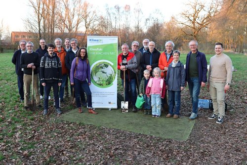Gruppe von Menschen steht bei einer Pflanzaktion neben einem Banner des KlimaPakt Kreis Coesfeld und Werkzeugen zum Pflanzen von Obstbäumen.