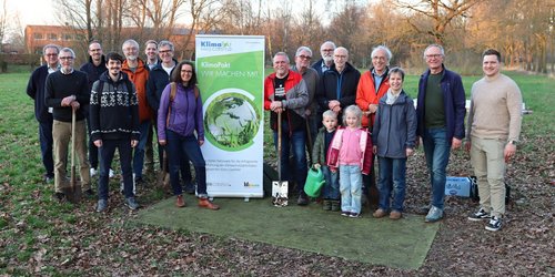 Gruppe von Menschen steht bei einer Pflanzaktion neben einem Banner des KlimaPakt Kreis Coesfeld und Werkzeugen zum Pflanzen von Obstbäumen.