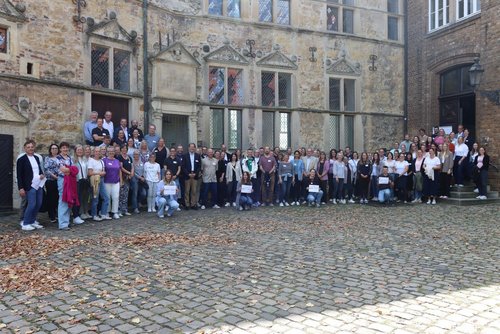 Große Gruppe von Mitarbeitenden der Jobcenter im Kreis Coesfeld bei der Jubiläumsfeier vor historischer Kulisse.