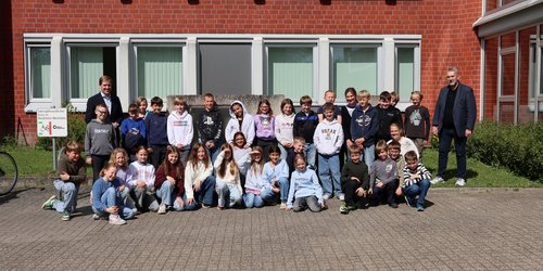 Eine Gruppe von Grundschulkindern steht gemeinsam mit Landrat Dr. Christian Schulze Pellengahr vor dem Kreishaus und blickt in die Kamera.