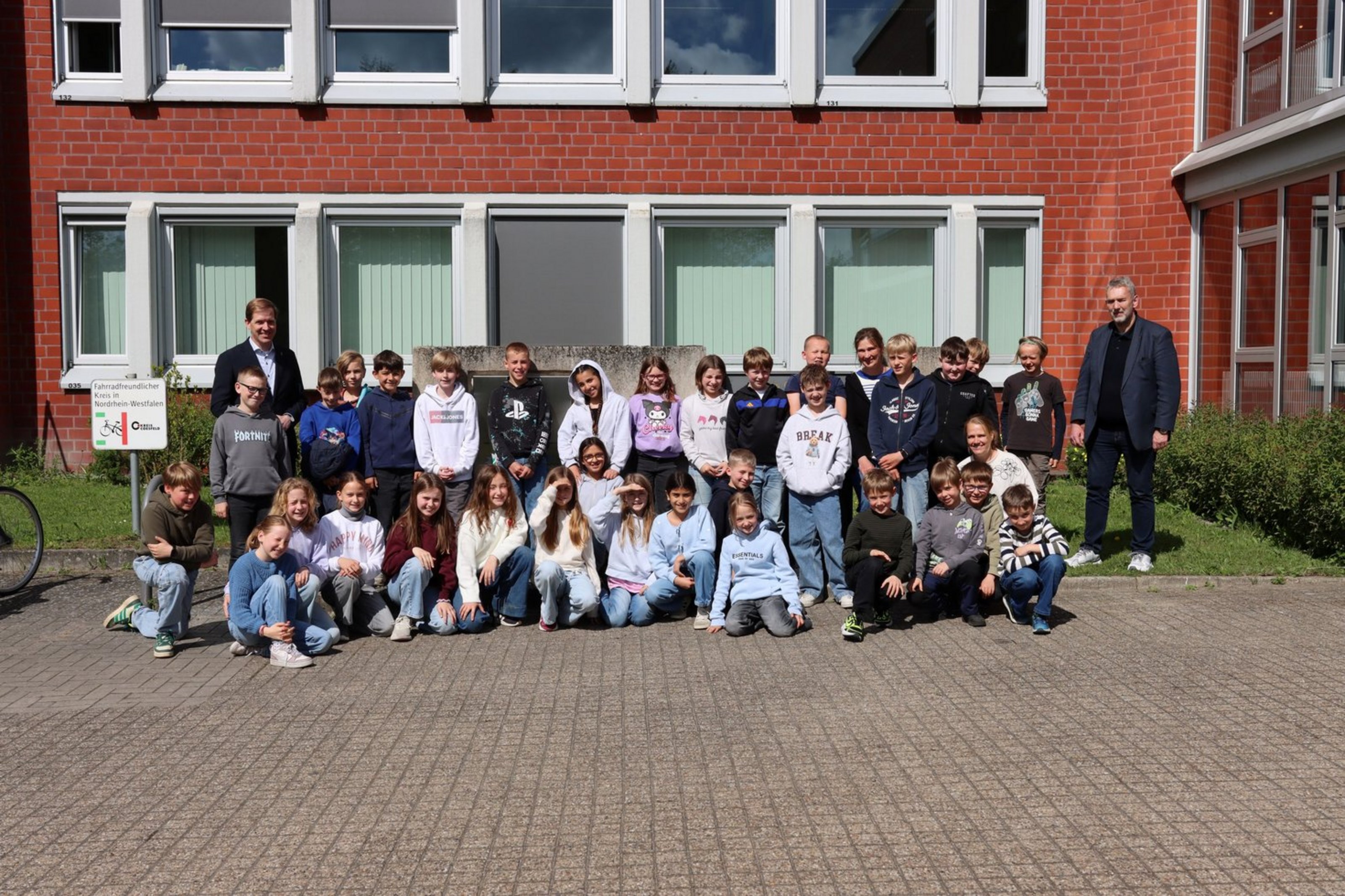 Eine Gruppe von Grundschulkindern steht gemeinsam mit Landrat Dr. Christian Schulze Pellengahr vor dem Kreishaus und blickt in die Kamera.