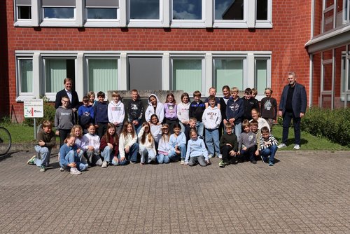Eine Gruppe von Grundschulkindern steht gemeinsam mit Landrat Dr. Christian Schulze Pellengahr vor dem Kreishaus und blickt in die Kamera.