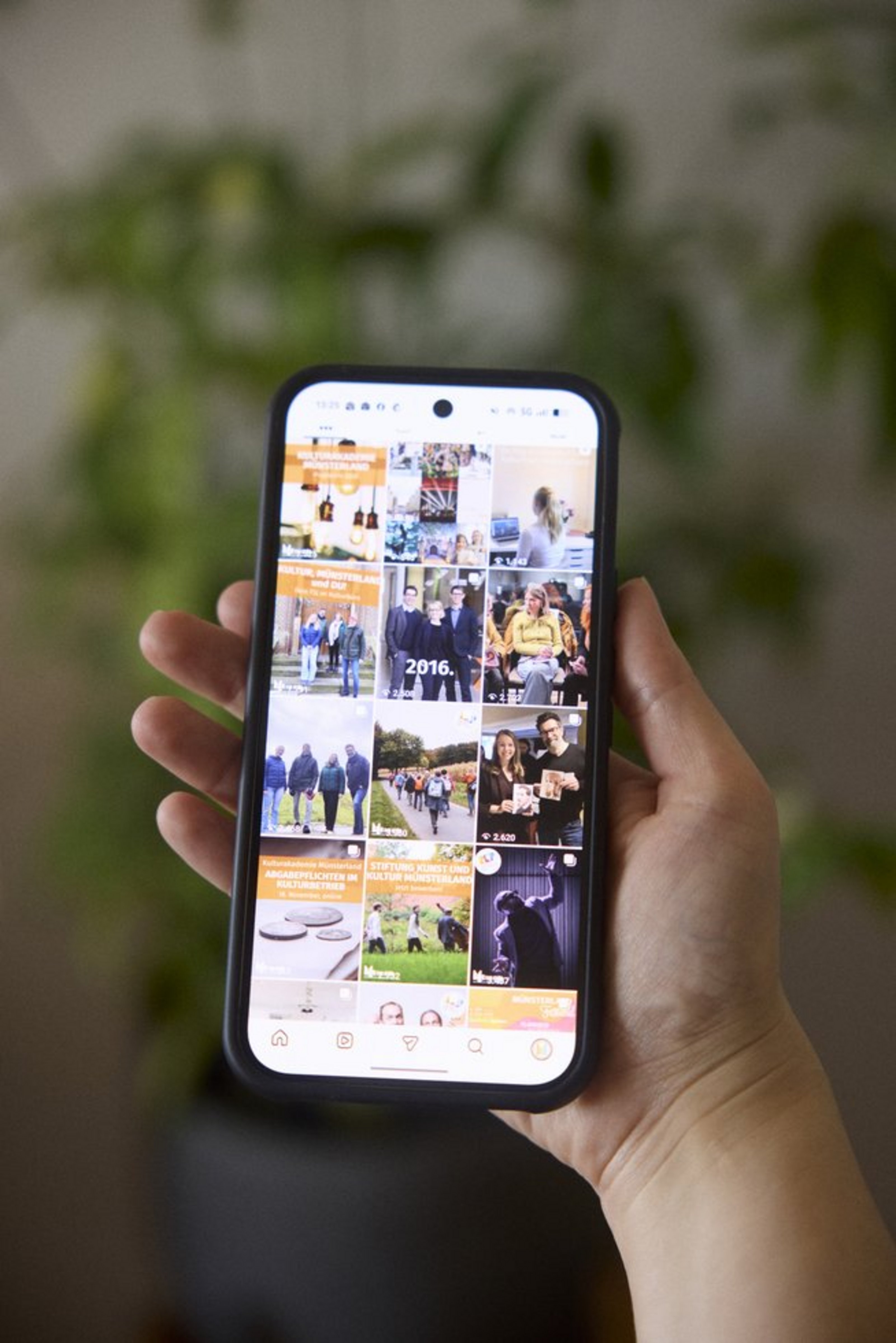 Auf einem Handybildschirm, der von einer Hand gehalten wird, ist ein Raster mit drei mal vier Fotos zu sehen.