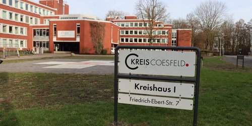 Vor einem großen geklinkerten Gebäude steht ein Schild mit der Aufschrift "Kreis Coesfeld. Kreishaus I. Friedrich-Ebert-Str. 7".