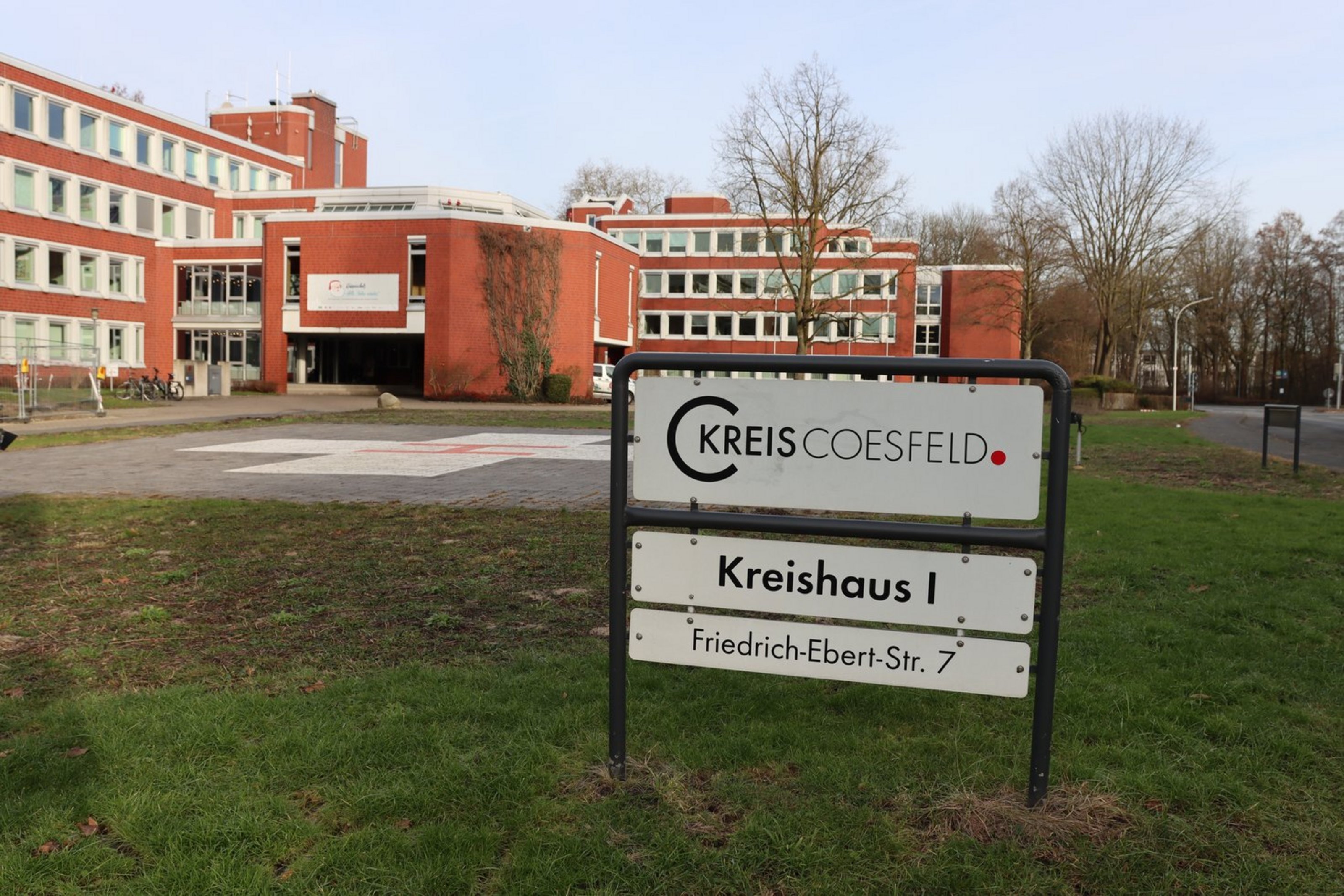 Vor einem großen geklinkerten Gebäude steht ein Schild mit der Aufschrift "Kreis Coesfeld. Kreishaus I. Friedrich-Ebert-Str. 7".