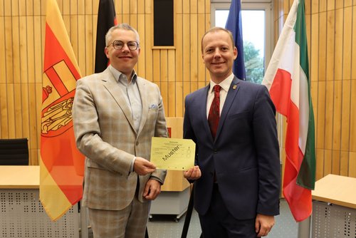 Dr. Linus Tepe und Jens Boehle präsentieren im Sitzungssaal das Muster eines Stimmzettels. 